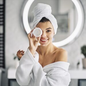 Woman with glowing skin applying natural skincare cream
